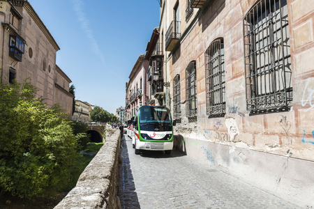 Granada, Spain - August 12, 2015: Tourist bus in the old town of Granada, near the Darro river.のeditorial素材