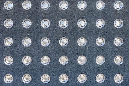 Round lights embedded in a wall of gray marbleの写真素材