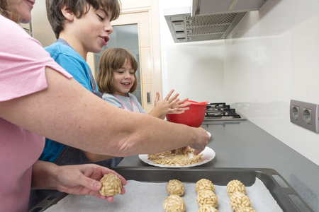 Family kneading marzipan for make panellets in the kitchen. Panellet are traditional desserts of All Saints holiday, known as Castanyada in Catalonia, Spainの写真素材