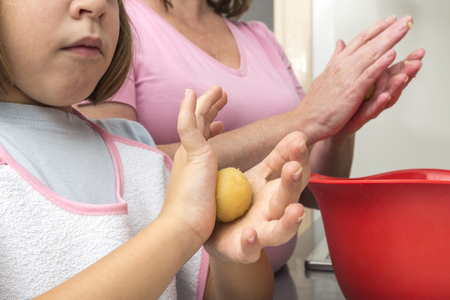 Mother and daughter kneading marzipan for make panellets  in the kitchen. Panellet are traditional desserts of All Saints holiday, known as Castanyada in Catalonia, Spainの写真素材