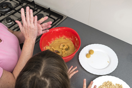Mother and daughter kneading marzipan for make panellets  in the kitchen. Panellet are traditional desserts of All Saints holiday, known as Castanyada in Catalonia, Spainの写真素材