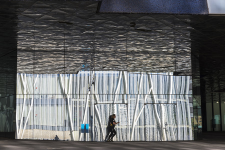 Barcelona, Spain - October 31, 2015: Woman running with buildings reflected in the glass producing abstract effectsのeditorial素材
