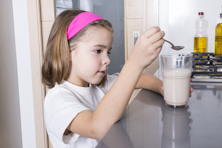 Little girl getting ready a glass of chocolate milkの写真素材