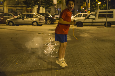 Boy exploding firecrackers at night to celebrate the festivity of Sant Joan on a street in Barcelona, Catalonia, Spainの写真素材