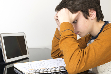 Teenage boy studying and using digital tablet at homeの写真素材
