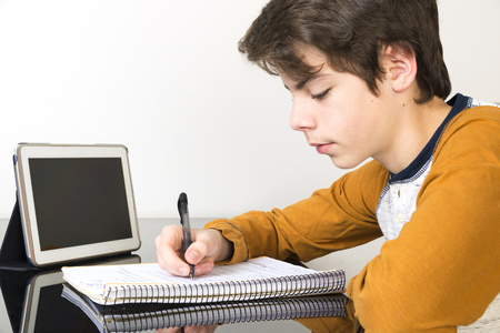 Teenage boy studying and using digital tablet at homeの写真素材