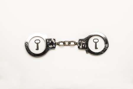 Close-up of a silver handcuffs with key on white backgroundの写真素材