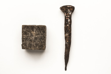 Close-up of old rusty nail and old wooden cube isolated on white backgroundの写真素材