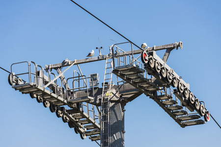 Cable way tower against the blue sky and seagulls above the pole in Barcelona, Catalonia, Spainの写真素材
