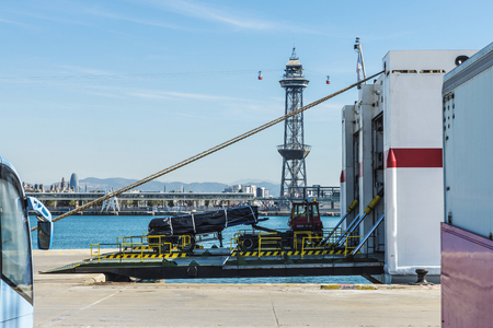 Truck going into the hold of a cargo ship with funicular tower in the background in the port of Barcelona, Catalonia, Spainの写真素材