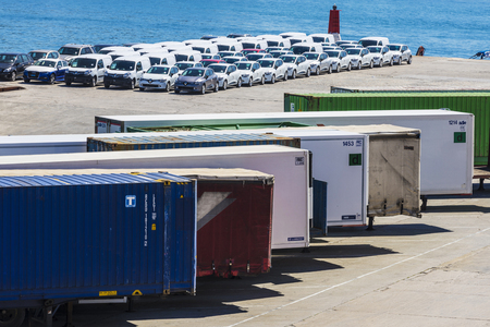 Barcelona, Spain - April 19, 2016: Containers and new cars parked in a row waiting to board at the port of Barcelona, Catalonia, Spainのeditorial素材
