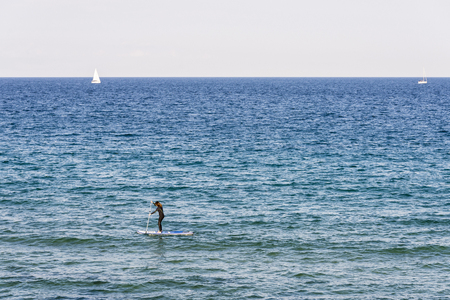 Barcelona, Spain - June 1, 2016: Girl with a wetsuit paddling on a surfboard in Barcelonaのeditorial素材