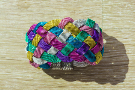 Bracelet intertwined with several colors on wooden floorの写真素材