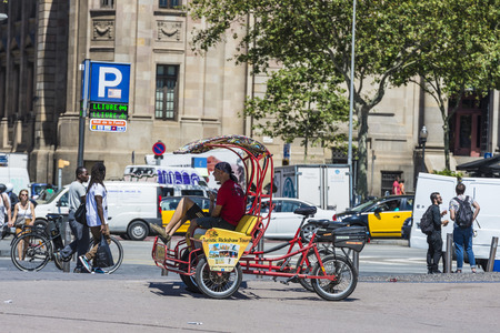 Barcelona, Spain - June 21, 2016: Rickshaw drivers resting on a ride while people walk in the old town of Barcelonaのeditorial素材