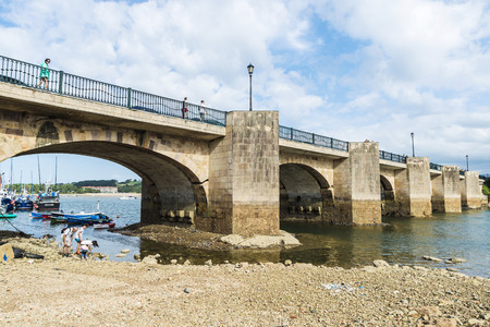 San Vicente de la Barquera, Spain - August 10, 2016: Family near fishing boats under the bridge in the harbor in the village of San Vicente de la Barquera in Cantabria, Spainのeditorial素材
