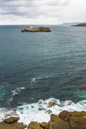 Rocky coastline along cliffs with the island of Mouro in the background in Santander, Cantabria, Spainの写真素材