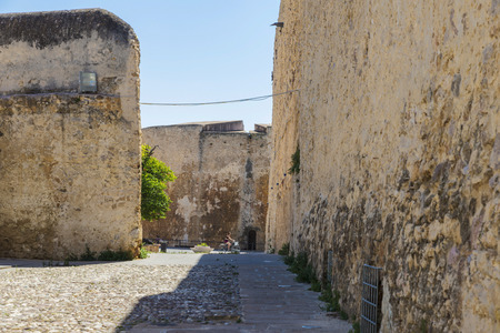 Street of the old historic town of Alghero where a girl rides a bicycle in Sardinia, Italyの写真素材