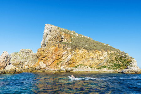 Estartit, Spain - June 24, 2016: Boat sailing with a man with the Medes islands in the background at the Costa Brava, Girona, Catalonia, Spainのeditorial素材