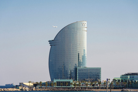 Barcelona, Spain - June 1, 2016: The W Barcelona hotel, also known as the hotel vela "sail hotel", designed by architect Ricardo Bofill, with an airplane flying next to this, located on the new entrance of Barcelona's Port.のeditorial素材