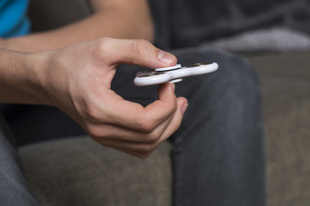 Young boy playing with fidget spinner toy to relieve stress sitting on the sofa at homeの写真素材