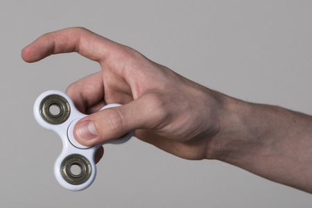 Young boy playing with fidget spinner toy to relieve stress isolated from the backgroundの写真素材