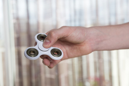 Young boy playing with fidget spinner toy to relieve stress at homeの写真素材