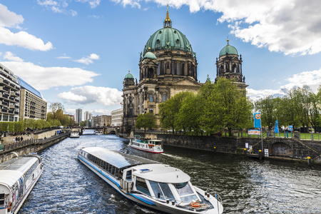 Berlin, Germany - April 13, 2017: The Berlin Cathedral (Berliner Dom) of Neobaroque style from the Spree river with boats sailing down and people walking around in Berlin, Germany.のeditorial素材