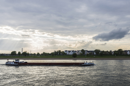 Merchant ship sailing on the Rhine River at dusk in Dusseldorf, Germanyの写真素材