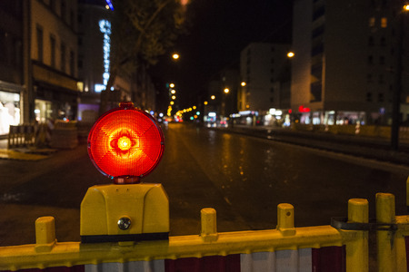 Fence with red warning light warning of a street under construction in Dusseldorf, Germanyのeditorial素材