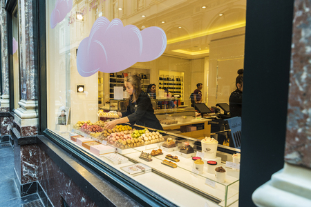 Brussels, Belgium - August 26, 2017: Girl places macaroons in the shop window of a candy shop in the Galeries Royales Saint Hubert in Brussels, Belgiumのeditorial素材