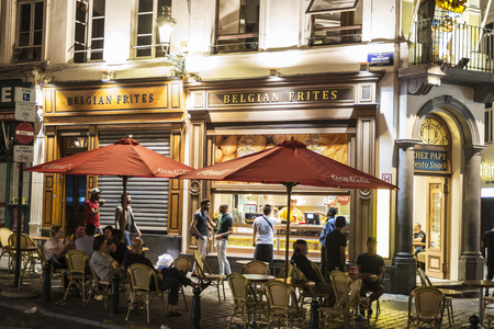 Brussels, Belgium - August 27, 2017: Street with a bar or restaurant specialized in chips with people at night located in the historic center of Brussels, Belgiumのeditorial素材