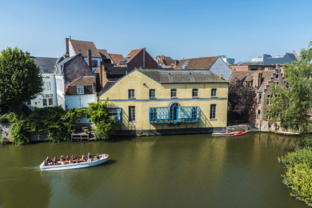Ghent, Belgium - August 29, 2017: Old houses along the Leie river with people sailing in a boat in the medieval city of Ghent, Belgiumのeditorial素材