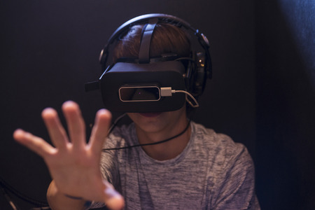 Teenager boy playing with 3d glasses in virtual reality videogame in a dark roomの写真素材