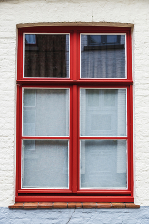 Red window of an old classic house in an old historic center of the medieval city of Bruges, Belgiumの写真素材