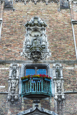Balcony of an old classic building with artistic statues in an old historic center of the medieval city of Bruges, Belgiumの写真素材