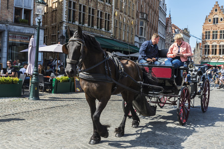 Bruges, Belgium - August 31, 2017: Carriage with horse carrying tourists on a street in the historic center of the medieval city of Bruges, Belgiumのeditorial素材