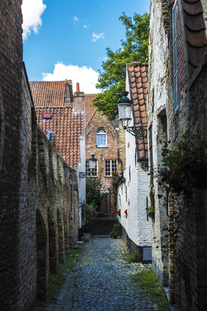 Perspective of a narrow street with old houses in an old historic center of the medieval city of Bruges, Belgiumの写真素材