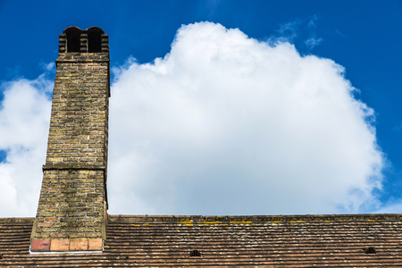 Old brick chimney against the sky and clouds as background in the medieval city of Bruges, Belgiumの写真素材