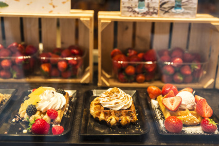 Display of a candy shop full of waffles with fruits like blackberries or strawberries in the medieval city of Bruges, Belgiumの写真素材