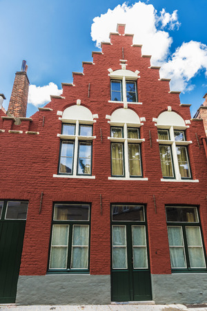 Facade of old historic red building in the medieval city of Bruges, Belgiumの写真素材