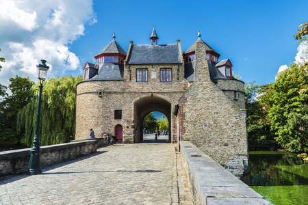 Ezelpoort (Donkey's gate), fortified gate on the river with people around, in the medieval city of Bruges, Belgiumの写真素材