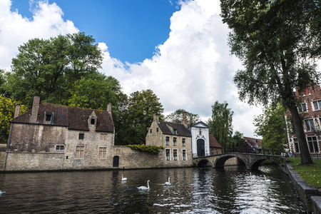 Convent of Sancta Elisabeth Sauve Garde along the river with white swans swimming in the medieval city of Bruges, Belgiumの写真素材