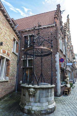 Old historic water well on a street in the medieval city of Bruges, Belgiumの写真素材