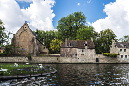 Convent of Sancta Elisabeth Sauve Garde along the river with white swans swimming in the medieval city of Bruges, Belgiumの写真素材