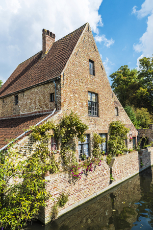 Old traditional houses along the river in the medieval city of Bruges, Belgiumの写真素材
