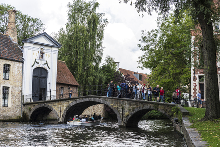 Bruges, Belgium - September 1, 2017: Convent of Sancta Elisabeth Sauve Garde along the river with people sailing in a tour boat in the medieval city of Bruges, Belgiumのeditorial素材