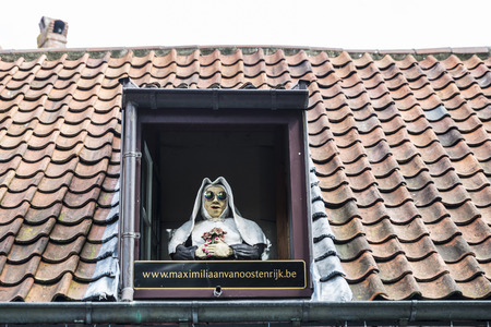 Bruges, Belgium - September 1, 2017: Nun statue with sunglasses on the window of a roof as advertising for a restaurant bar in the old historic center of the medieval city of Bruges, Belgiumのeditorial素材
