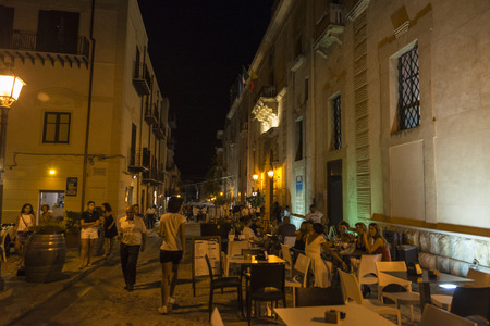 Castellammare del Golfo, Italy - August 6, 2017: Street of the old town with people walking and having a drink at night in Castellammare del Golfo in Sicily, Italyのeditorial素材