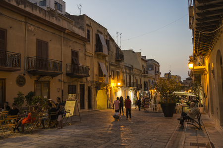 Castellammare del Golfo, Italy - August 6, 2017: Street of the old town with people walking and having a drink at night in Castellammare del Golfo in Sicily, Italyのeditorial素材