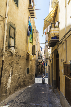 Cefalu, Italy - August 8, 2017: Narrow street with with a scooter circulating in the old town of the historic village of Cefalu in Sicily, Italyのeditorial素材